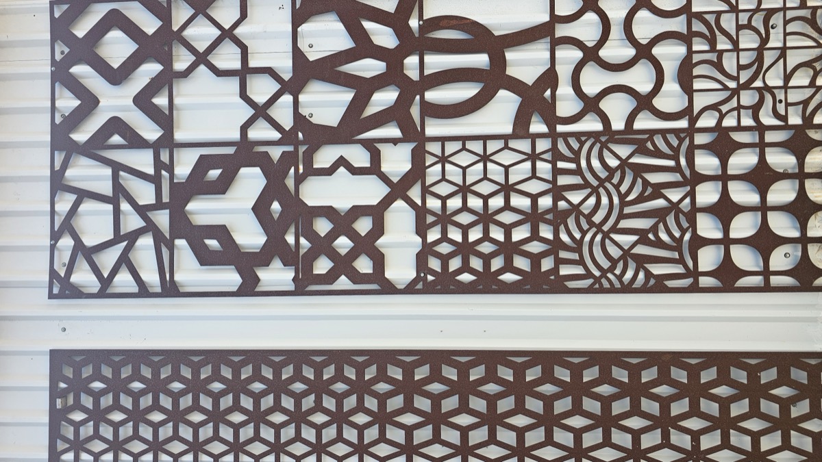 Panel celosía con patrones geométricos cortados con láser, acabado oxidado